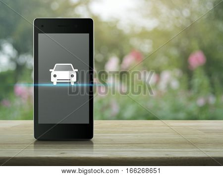 Car flat icon on modern smart phone screen on wooden table over blur pink flower and tree Internet business service transportation concept