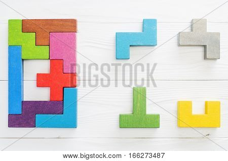 IQ test. Choose correct answer. Logical tasks composed of colorful wooden shapes top view. Children's educational logical task flat lay. Visual conundrum find the missing piece of the proposed.