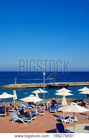 AGIOS NIKOLAOS, CRETE - SEPTEMBER 17, 2016 - Tourists relaxing on the Hotel Mirabello sun terrace with the harbour to the rear Agios Nikolaos Crete Greece Europe, September 17, 2016.