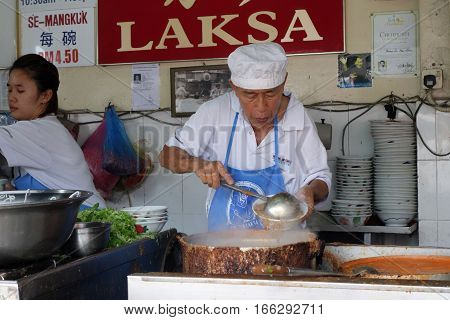 Hawker Vendor At Their Assam Laksa Noodle Stall In Air Itam, Penang