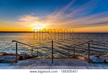 Steps on a beach with sunset on the ocean sea. Landscape photo of sunrise or sunset on a natural beach in Piran Slovenia.