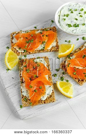 Homemade Crispbread toast with Smoked Salmon, Melted Cheese and cress salad. on white wooden board.