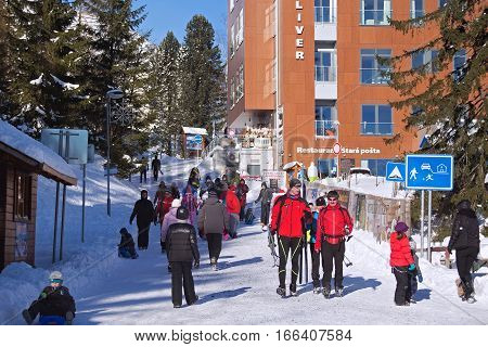 SLOVAKIA, STRBSKE PLESO - JANUARY 06, 2015: Skiers and other active tourists in Strbske Pleso. The village is a favorite ski tourist and health resort in the slovakian part of High Tatras mountains.