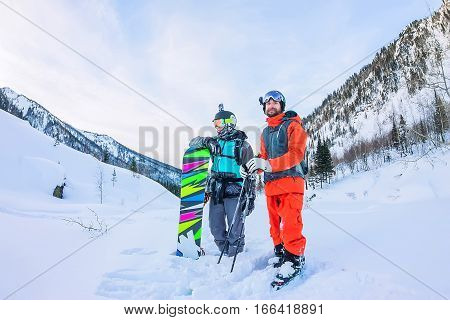 Freeriders Male Skiers And Snowboarders Are In The Mountains In The Snow