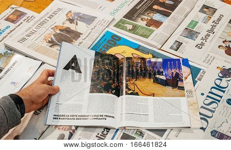 PARIS FRANCE - JAN 21 2017: Man reading about the first Press-Confirence of Donald Trump above major international newspaper journalism featuring headlines with Donald Trump inauguration as the 45th President of the United States in Washington D.C