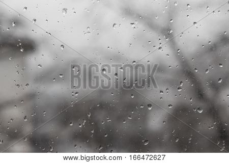 Raindrops on glass in rainy weather gray