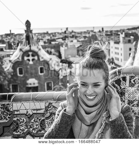 Woman In Barcelona Listening Audioguide While Sitting On Bench