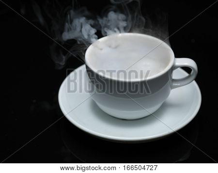 warm cup of coffee with smoke on black background