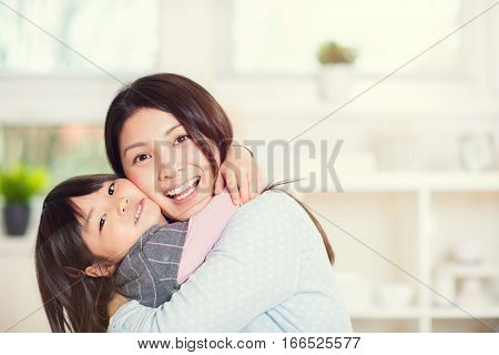 Portrait of happy japanese mother hugging with her cute little daughter at home