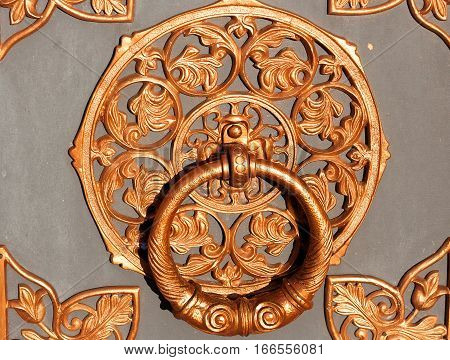 Brass handle on the door of the Church. Door knocker. Old vintage ornament pattern on the door.