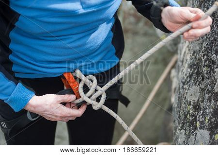 Climber Woman In Safety Harness Tying Rope In Bowline Knot