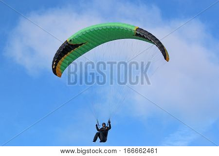 Paraglider flying his wing in a blue sky