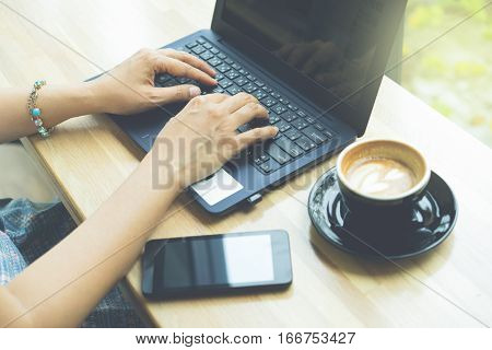 Businesswoman working with modern devices laptop computer and mobile phone in coffee shopwoman's hands using smart phone in interior woman at her workplace using technology .