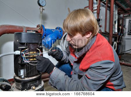 St. Petersburg Russia - March 5 2013: Industrial Pump Repair Services the technician connects the motor wires.