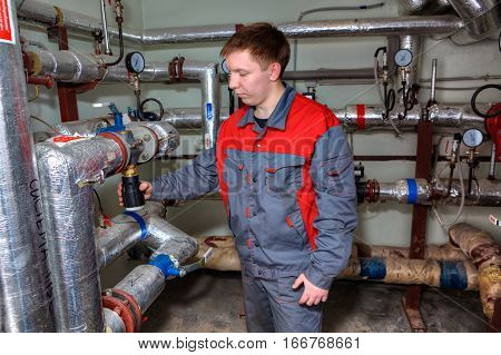 St. Petersburg Russia - March 5 2013: Mechanical Engineer in the process maintenance of the heating system in the basement of an apartment house.