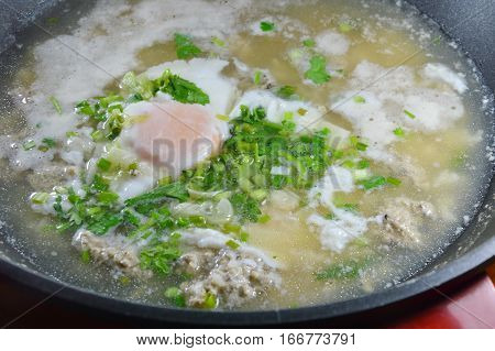 egg on hot boiled rice with minced pork dressing parsley in pot