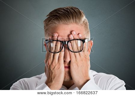 Man's Hand Over The Face With Eyeglasses Over Grey Background