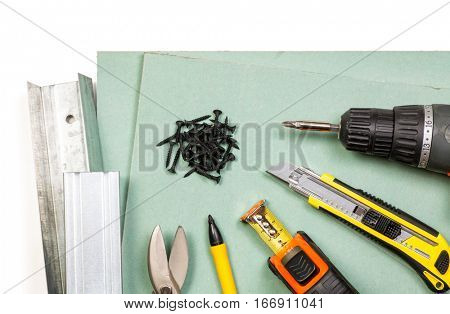 Plasterboard tools set with screws tape measure screwgun cutter marker pen metal studs and snips on white background