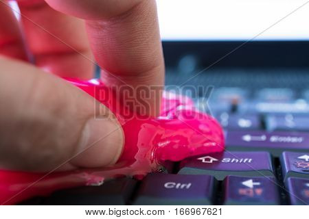 Keyboard cleaning gel in work. Hand and pink gel.