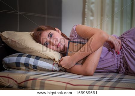 Beautiful young asian woman laying in bed sad after violence
