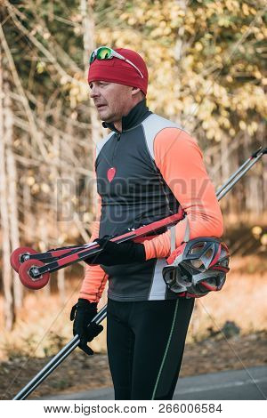 Training An Athlete On The Roller Skaters. Biathlon Ride On The Roller Skis With Ski Poles, In The H