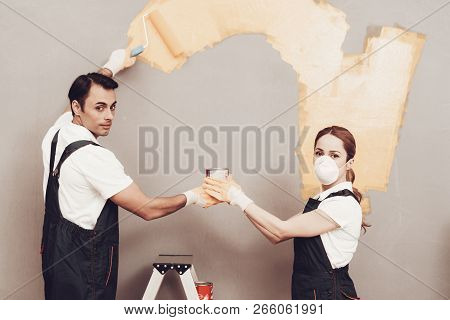 Master Painter. Gray Wall. Cardboard Boxes And Construction Ladder. Man And Woman In Respirators. Ma