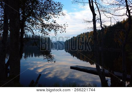 Nature of Sweden in autumn, Calm Stora Kedjen lake with wooden bridge and reflecting forest, Peaceful outdoor image