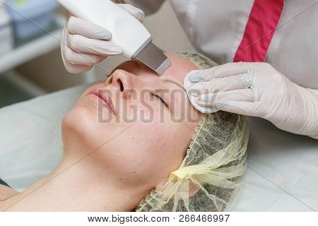 Cosmetologist Doing Procedure Cleaning Of Face With Ultrasonic Scrubber In Beauty Salon