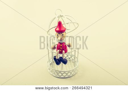 Metal Cage And Little Puppet Pinocchio Made Of Wood