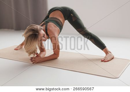 Attractive Young Female Bending Forward With Wide Spread Legs While Doing Yoga At Home