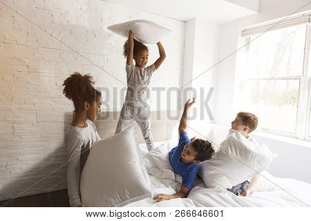 Large Group Of Friends Taking Goog Time On Bed With Pillow Fight