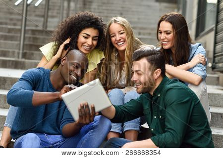 Multi-ethnic Group Of Young People Looking At A Tablet Computer Outdoors In Urban Background. Group 