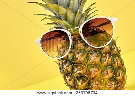 Funny Fresh Pineapple Wearing Sunglasses. Hipster Pineapple With Sunglasses Against A Yellow Backgro