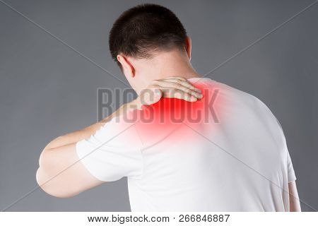 Neck Pain, Man Suffering From Backache On Gray Background, Painful Area Highlighted In Red