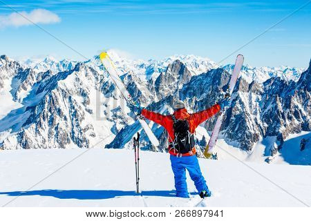 Ski in winter season, mountains and ski touring man on the top in sunny day in France, Alps above the clouds.
