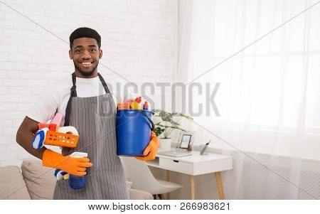 Professional Cleaning Service. Black Man Holding Sponges And Detergents In Washing Gloves, Copy Spac