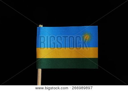 A Official Flag Of Rwanda On Toothpick On Black Background. A Horizontal Tricolour Of Blue, Yellow A