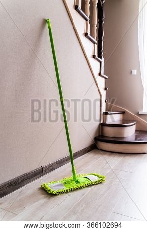 Green Mop On A Wall And Stairs Background. Cleaning Living Room.