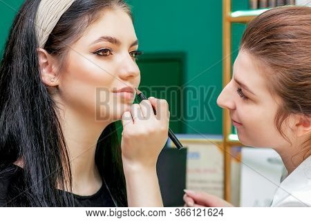 Makeup Artist Makes Outline With Lip Pencil On Lips Of Model In Beauty Salon.