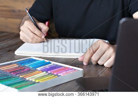 Person Learning Online Painting With Pensil And Pastel Crayon On White Sheet Of Paper In Front Of La