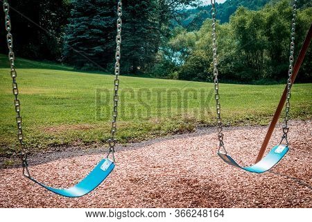 Empty Swings On A Swingset At A Park During The Summer
