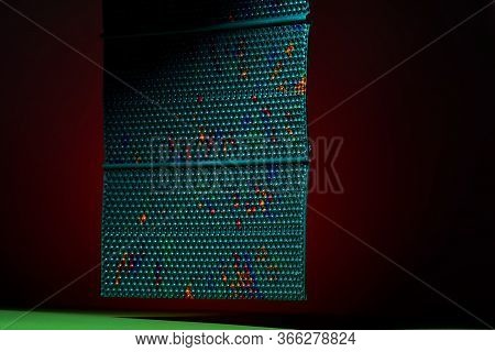 A Green Massage Mat On A Dark Red Background Hangs In The Air. Advertising And Subject Shooting. For