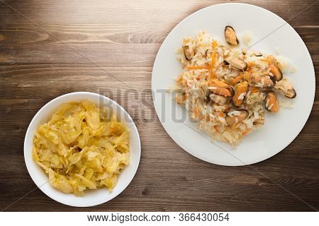 Rice With Mussels And Carrots On A White Plate. Rice With Mussels And Carrots On A Borwn Wooden Back