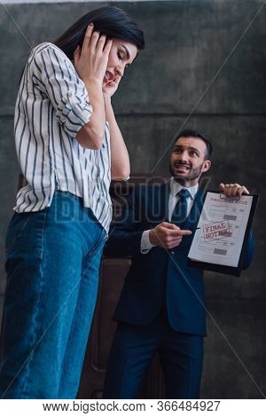 Low Angle View Of Angry Collector Pointing At Documents With Foreclosure And Final Notice Lettering 