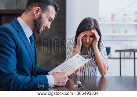 Upset Woman Covering Face Near Collector Smiling And Reading Document With Bankruptcy Lettering At T
