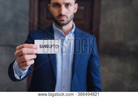 Selective Focus Of Collector Showing Card With Bankruptcy Lettering And Looking At Camera
