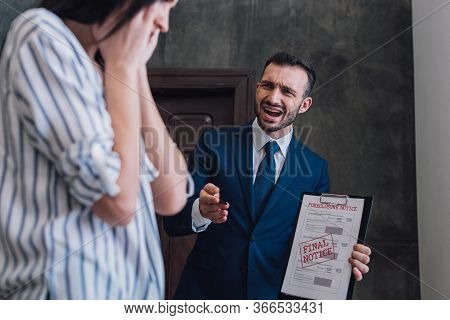 Selective Focus Of Angry Collector With Documents With Foreclosure And Final Notice Lettering Shouti