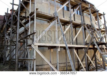 Wooden Scaffolding During The Construction Of A Large House Or Cottage Outside