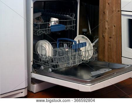 Interior Of A Kitchen With Washine Machine Loaded With Dishware