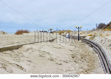 Sandy Boardwalk. Lighting Lights. Walking Women. Movement Of Dunes. Beach In Winter